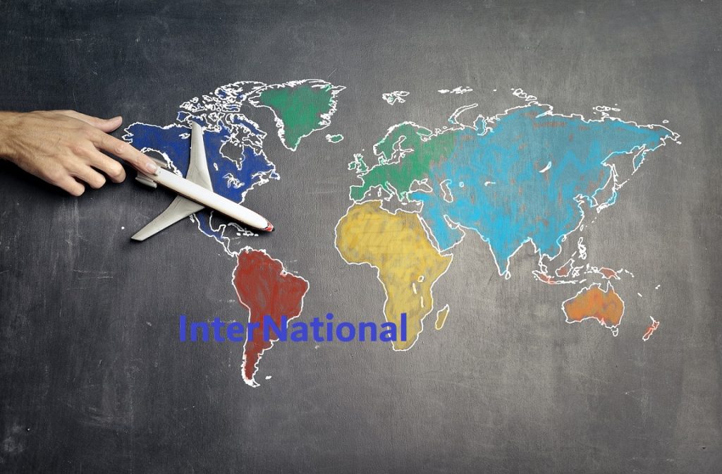 Hands over a world map on a chalkboard, representing international program management